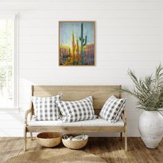 a living room scene with focus on the couch and cactus painting hanging above it's head