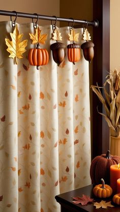 three pumpkins are hanging on the curtain rod in front of a window with fall leaves