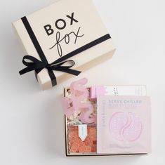 the box is open and has pink items in it, including a soap bar with black ribbon