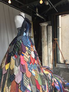 a mannequin is covered in many different colored ties and pieces of clothing on display