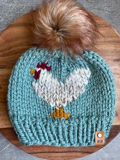 a blue knitted hat with a white chicken on it