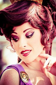 a woman wearing a purple dress and a gold crown on top of her head is posing for the camera