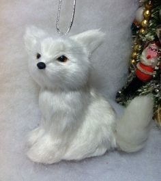 a white stuffed animal sitting next to a christmas tree