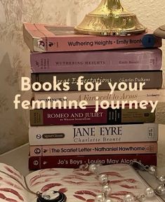 a stack of books sitting on top of a white table next to a gold lamp