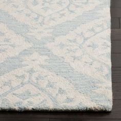 a white and blue rug on top of a wooden floor