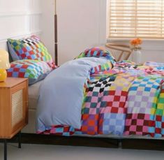 a bed room with a neatly made bed and colorful comforter on top of it