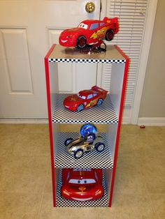 three cars are stacked on top of each other in a toy car display case that is decorated with black and white checkered paper