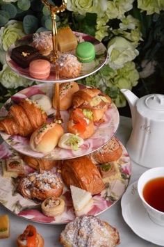 three tiered trays filled with pastries next to a cup of tea