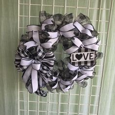 a black and white wreath with the word love is hanging on a green tile wall