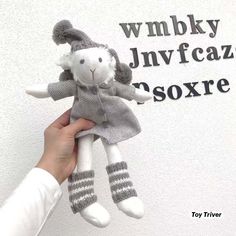 a person holding a stuffed animal in front of a wall that says wmbly jnvfccaz soxre