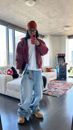 a person taking a selfie in a living room with a couch and large windows