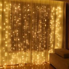 a living room with lights on the curtains and a couch in front of a window