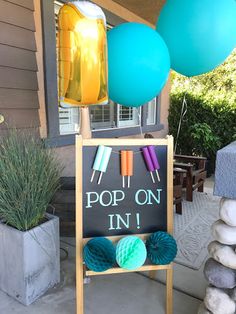 a sign that says pop on in front of some balloons and yarn ball holders outside