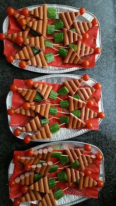 two trays filled with hot dogs and veggies on top of tin foil