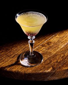 a glass filled with liquid sitting on top of a wooden table