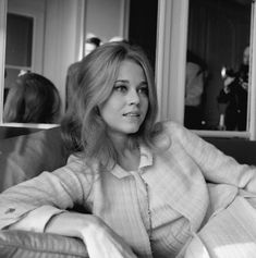 a black and white photo of a woman sitting on a couch