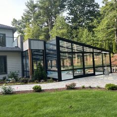 a glass house sitting in the middle of a lush green field