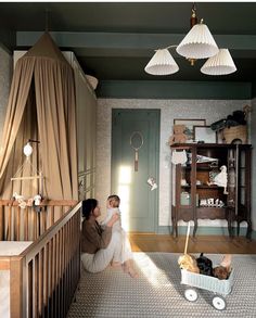 a woman holding a baby in her arms while sitting on the floor next to a crib