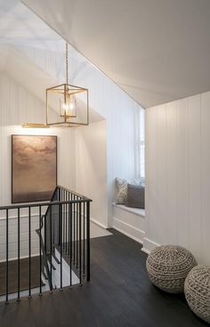 a hallway with white walls and wood floors, black iron handrails and a painting on the wall