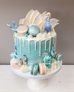 a blue and white cake with icing on it's sides, topped with an ice queen figure