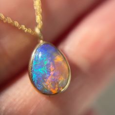 Crystal opal necklace by NIXIN Jewelry hanging in front of grey backdrop Unicorn Tears, Purple Opal, Under The Dome, Crystal Opal, Green Hues, A Unicorn, Gold Polish, Opal Crystal, Australian Opal