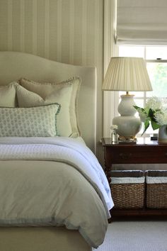 a white bed sitting next to a window with two lamps on top of each side