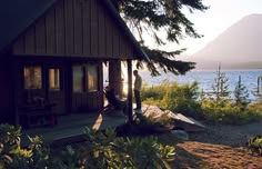 a man sitting in a hammock on the porch of a cabin next to water