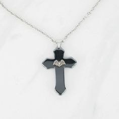 "Add a touch of traditional gothic style to your wardrobe with this cross pendant necklace. It would make a great addition to any dark jewelry collection! 💀 DESCRIPTION: This pendant necklace features a large cross made from hematite that was adorned with a small bat stamping. The cable chain was finished with a lobster clasp. 💀 SIZE & MATERIALS: The stamping was made from oxidized sterling silver plated brass. The chain was made from stainless steel and measures 18\" long. If you would li Traditional Goth, Bat Pendant, Necklace Traditional, Dark Jewelry, Hematite Stone, Goth Jewelry, Wing Necklace, Halloween Accessories, Black Chain