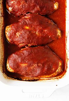 two pieces of meat covered in marinara sauce in a white casserole dish