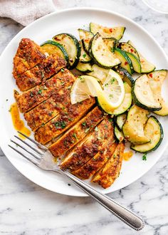 grilled chicken with zucchini and squash on a white plate next to a fork