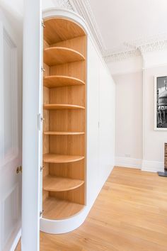 an empty room with wooden shelves and white paint on the walls, along with hard wood flooring