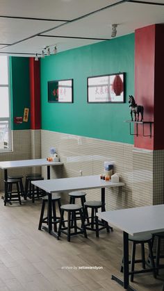 tables and stools are lined up against the wall in an empty room with colorful walls