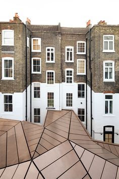 an upside down view of a building with many windows and roof tiles on the ground