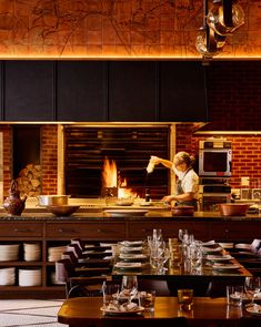 a chef is cooking in the kitchen with many plates and glasses on the table next to him