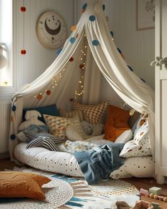 a child's bed with a canopy over it and pillows on the floor next to it