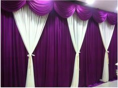 purple and white drapes are hanging on the wall