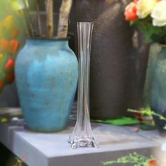 two vases sitting on top of a table next to each other with flowers in them