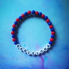 a red, white and blue beaded bracelet with the word barcelona written on it