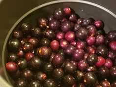 a bucket filled with lots of shiny red and purple balls on top of a table