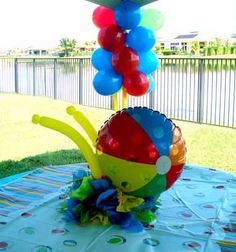 a table topped with balloons and a vase filled with colorful flowers on top of it