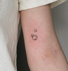 a person with a small tattoo on their arm that has an image of two bubbles in it