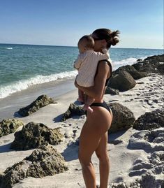 a woman holding a baby on the beach