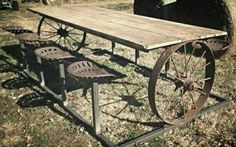 an old wooden table with four chairs and a wagon wheel on the ground next to it