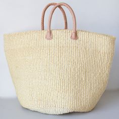 Sisal is a flowering plant that has been cultivated and naturalized in Kenya, and the strong fibers that come from it are used to make various items from rope to bags. These durable baskets can handle a heavy load without breaking a sweat while looking handsome at the same time! Woven from natural sisal plant fibers with leather handles. A Kenyan market artisan partnership. Learn more about our artisans' handmade products here. Details: 14" T 20" W Large 12" T 18" W Medium Colors and designs var Natural Bucket Bag With Braided Handles For Market, Large Natural Straw Bag, Large Natural Eco-friendly Straw Bag, Beige Basket Bucket Bag With Rolled Handles, Large Natural Straw Bag For Daily Use, Beige Straw Bag With Leather Handles For Market, Beige Basket Beach Bag With Rolled Handles, Natural Basket Bag With Rolled Handles, Beige Basket-shaped Bucket Bag For Market