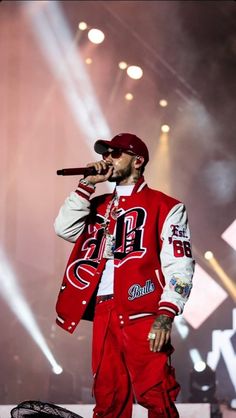 a man in red and white outfit holding a microphone on stage with lights behind him