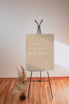 a welcome sign sitting on top of a wooden floor next to a vase with flowers