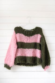 a green and pink sweater hanging on a white wall