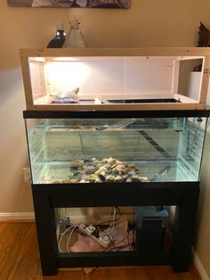 a fish tank with rocks in it on top of a wooden floor next to a wall