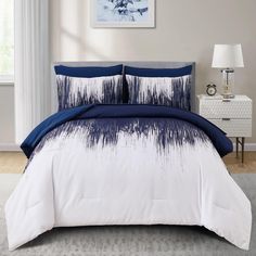 a bed with blue and white comforters in a bedroom next to a painting on the wall