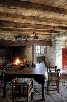 an old fashioned dining room with stone walls and flooring, wood beams on the ceiling